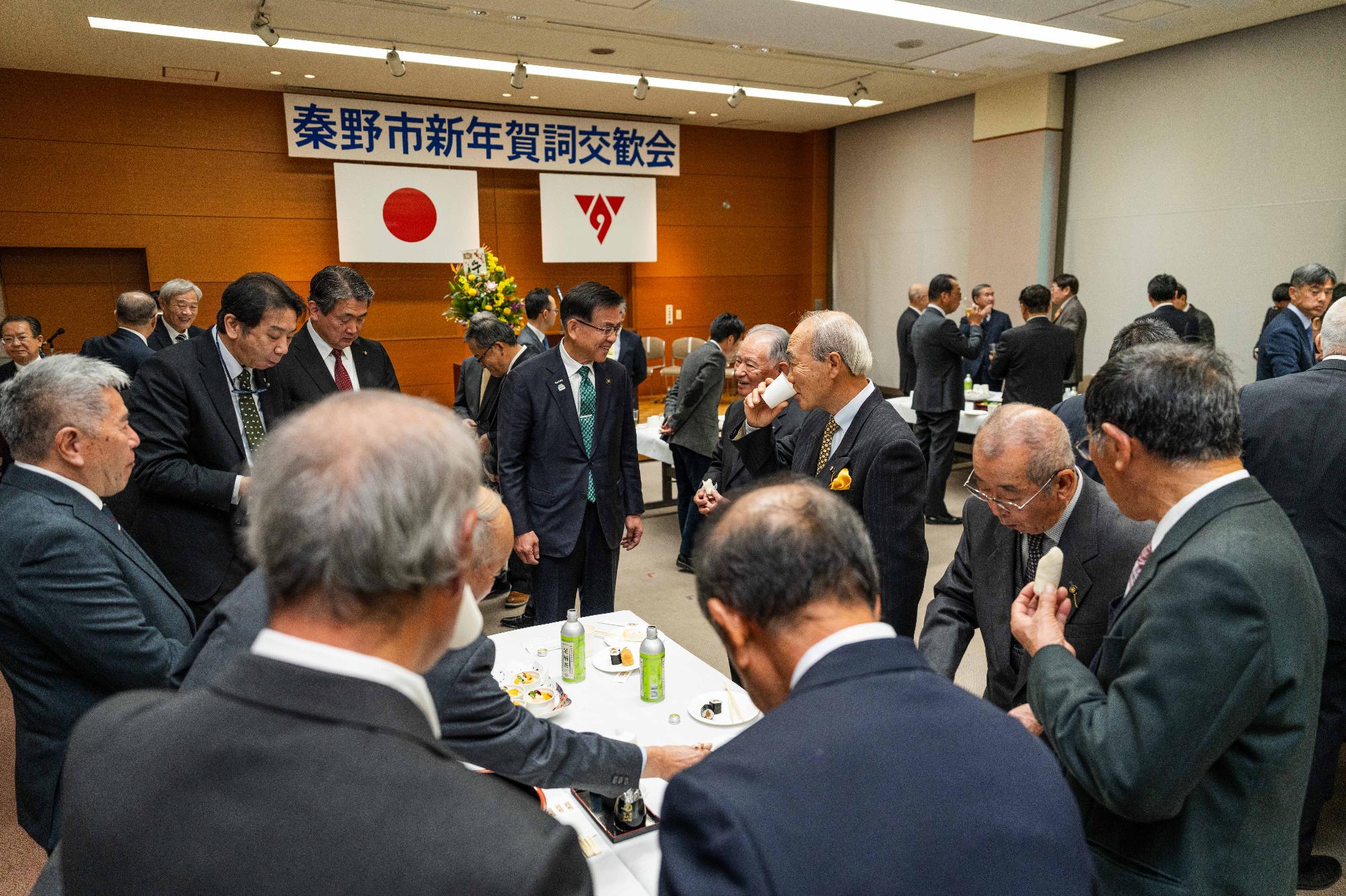 テーブルを囲むスーツの男性多数と談笑する市長。