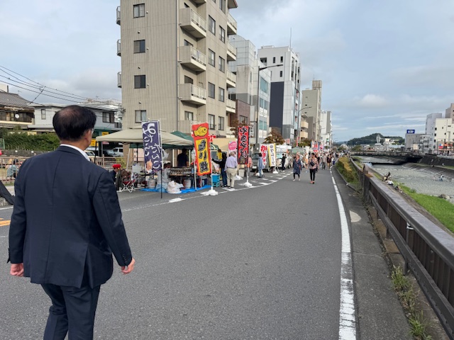 水無川沿いの道路上を歩く市長の後ろ姿