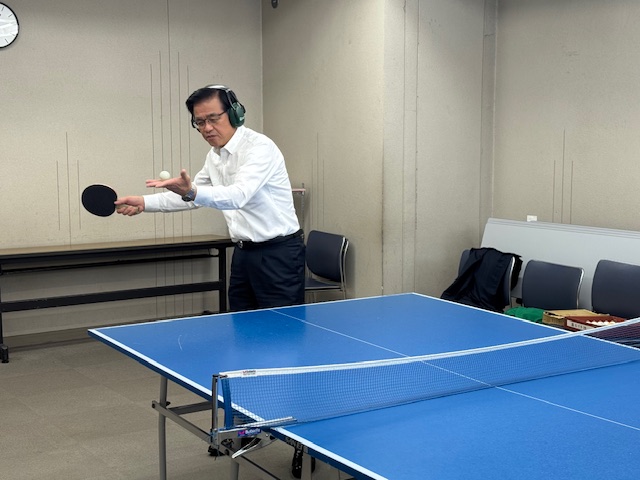 ヘッドホンをつけてデフ卓球を体験する市長、これからサーブを打とうとしている