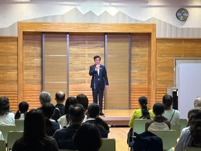 大勢の座った観客の前で演奏する市長