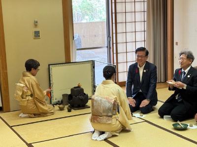 茶を点てる着物の女性とお茶を提供する着物の女性、受け取る市長とスーツの男性