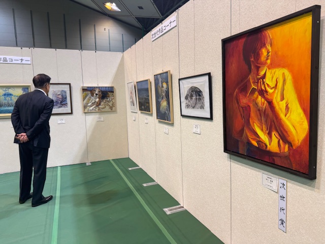 市展に出品された多数の絵画を鑑賞する市長の後ろ姿