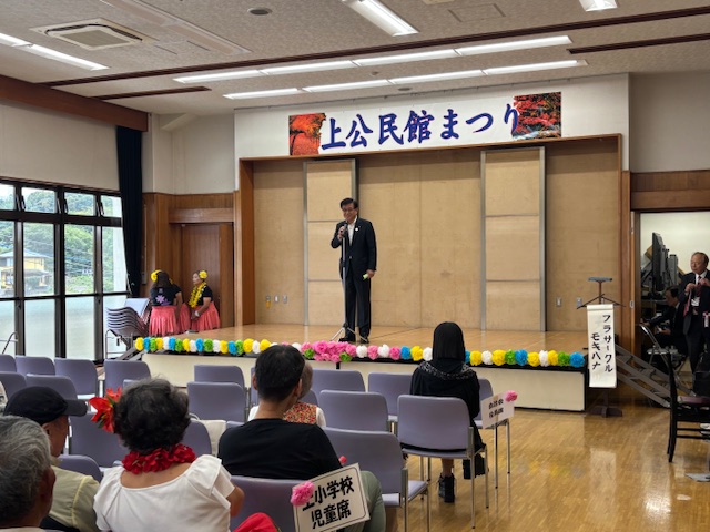 壇上で挨拶する市長とそれを聞く来場者数名