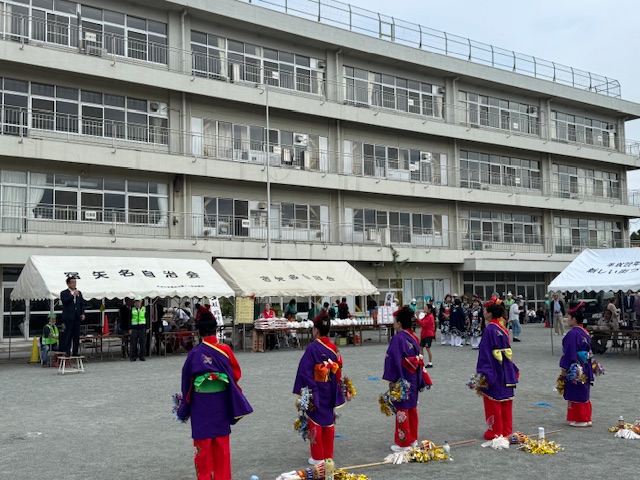 校庭で挨拶する市長を見ている着物姿で踊りの道具を持つ5人の女性