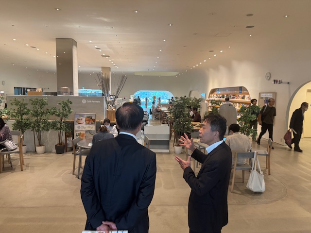 多くの人が行きかう施設を見学する市長とそれを説明するスーツの男性