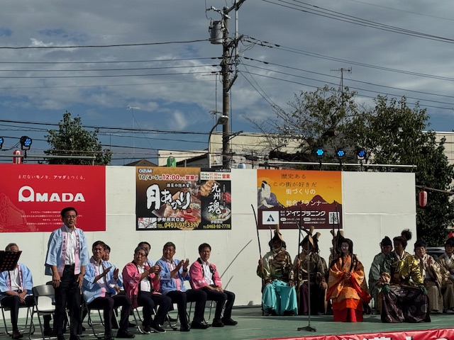 立って礼をするはっぴすがたの市長とその様子に拍手する来賓の男性たち
