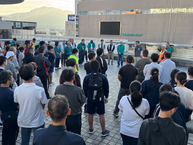 拡声器を持って話をする市長とそれを囲んで聞く多くの市民