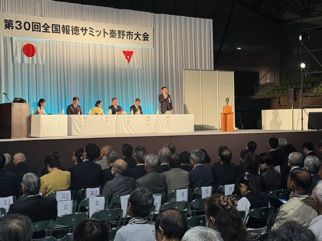 白いクロスのかかった机に横一列に5人が座り、一番右端に市長が立って話をしている。手前には観客が多数座る。