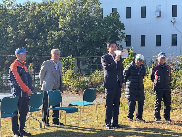 拡声器を持って話をする市長とその周辺に役員の男性数名