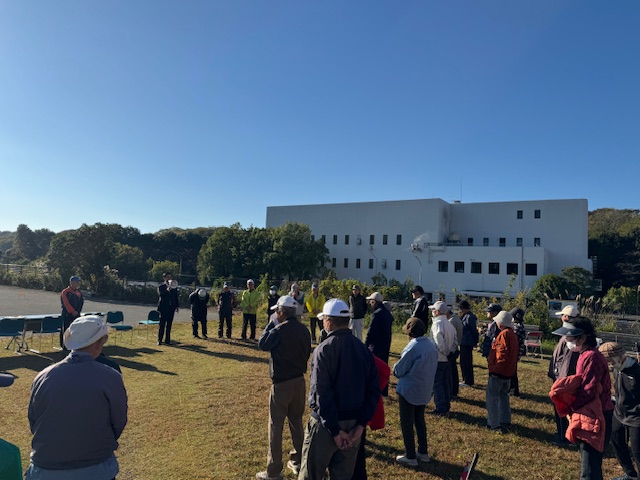 青空の下市長の挨拶を聞く高齢の参加者多数