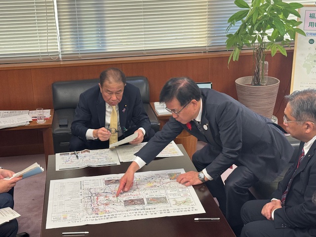 国土交通省大臣政務官へテーブルに広げた地図を指さして説明する市長