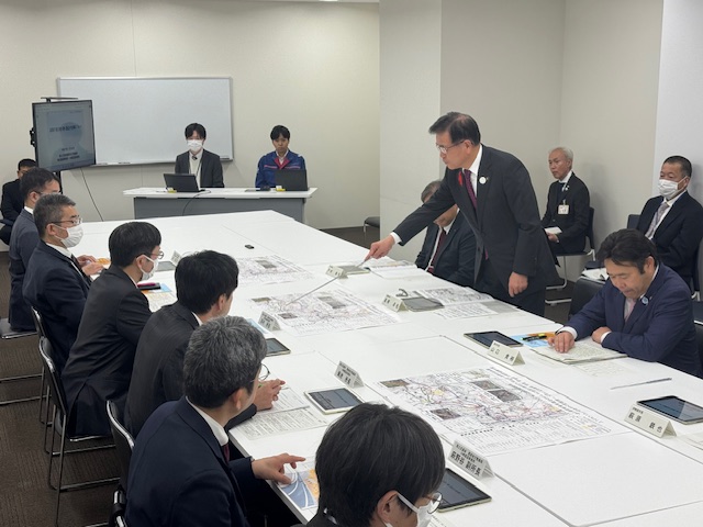横浜、川崎国道事務所の所長及び職員へテーブルに資料を広げて説明する市長