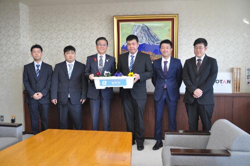 中央に市長と一緒にプランターを持ったスーツの男性とその左右に2人ずつ並んでいる。