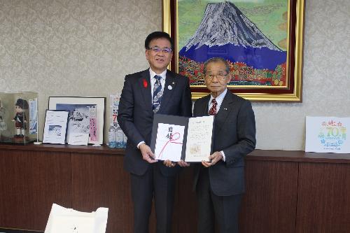 感謝状と目録を持って立つ市長とスーツの男性