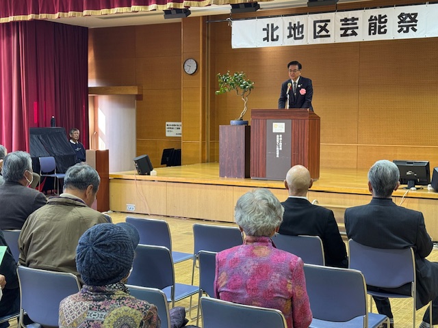 ステージの上で挨拶する市長とそれを聞く椅子に座った高齢者数名