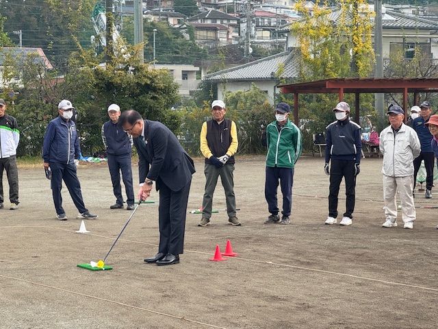 ターゲットバードゴルフの体験をする市長、その様子を男性のプレイヤーが7人見守る