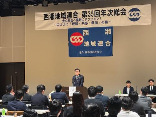 市長が立って挨拶をしている。背後に西湘地域連合第35回年次総会の横断幕と同連合の旗が掲げられている。