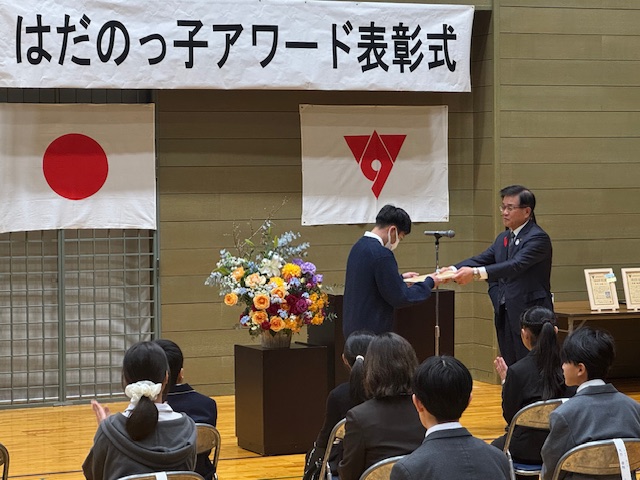 受賞者の子どもに木製の賞状を渡す市長。