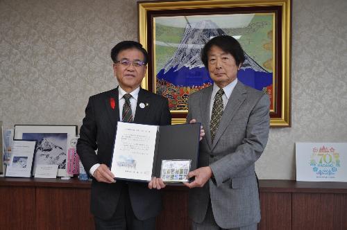 市長とスーツの男性が感謝状と野鳥の絵の卓上カレンダーを一緒に持って立っている。