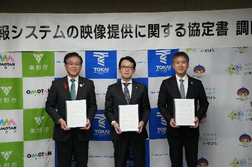 協定書を持った3人の男性が並んで記念写真を撮っている