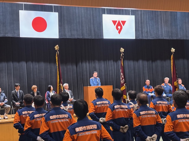 制服を着た消防団団員が整列している前で消防の制服を着た市長が挨拶をしている
