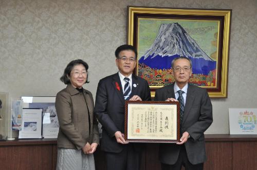 賞状を持って立つ市長と右側にスーツの男性、左側に女性