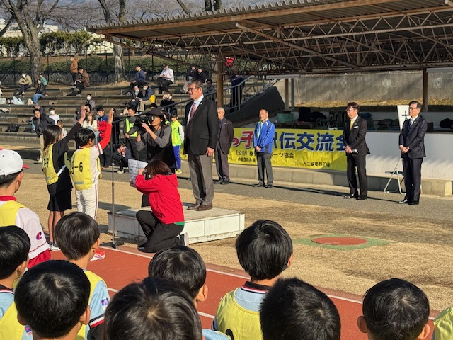 陸上競技場で2人の子どもが選手宣誓をしている