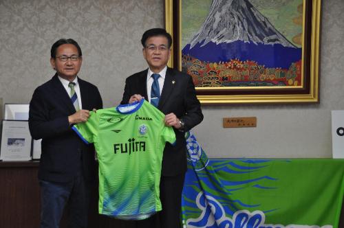 市長とスーツの男性がサッカーベルマーレのユニフォームを持って立っている。