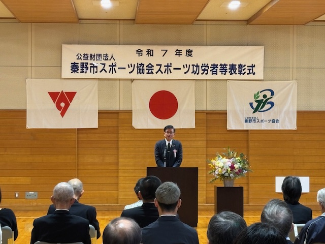 演台の後ろで挨拶する市長。その背後に秦野市スポーツ協会スポーツ功労者等表彰式の横断幕