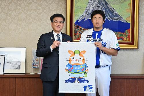 市長と横浜ベイスターズの投手がマスコットのタペストリーを持って立っている