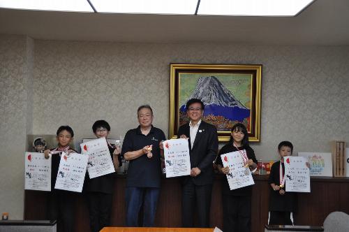 秦野市スポーツチャンバラ協会の4人の子供と監督が賞状を持って市長と記念写真を撮る様子
