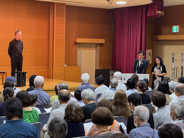 アコーディオン奏者の男性を迎えて観客に挨拶する市長