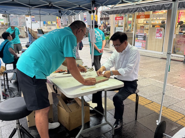 秦野駅北口で開催されたマルシェでミニ畳作り体験をする市長