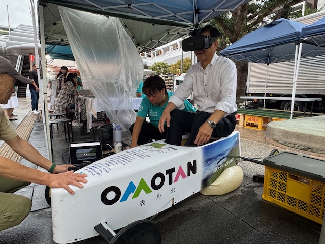秦野駅北口で開催されたマルシェでVRを使ったソープボックスダービーを体験する市長