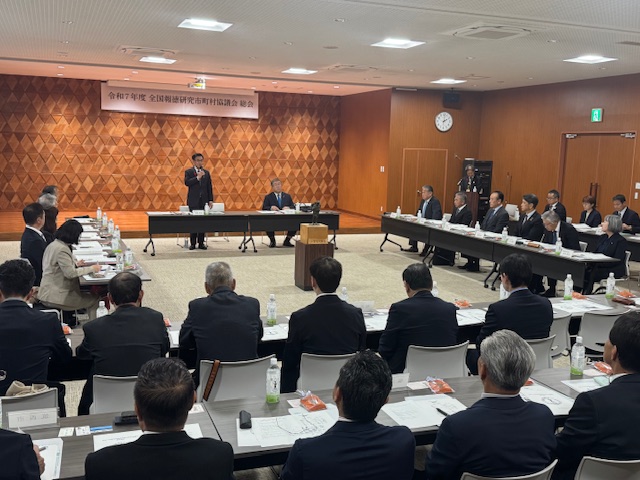 会議室で大勢のスーツの出席者に向けて市長が挨拶をしている写真