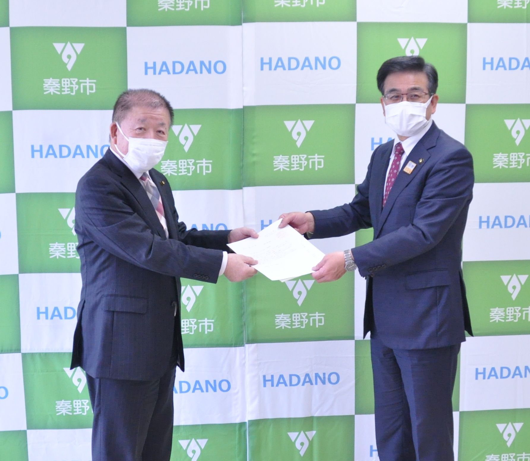 秦野市のバックボードの前で、議長から市長へ要望書の提出が行われている写真