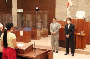 発言者席に立つ女の子が前方のスーツ姿の正副議長に向かって質問し、二人は真剣に耳を傾けている様子が写っている写真