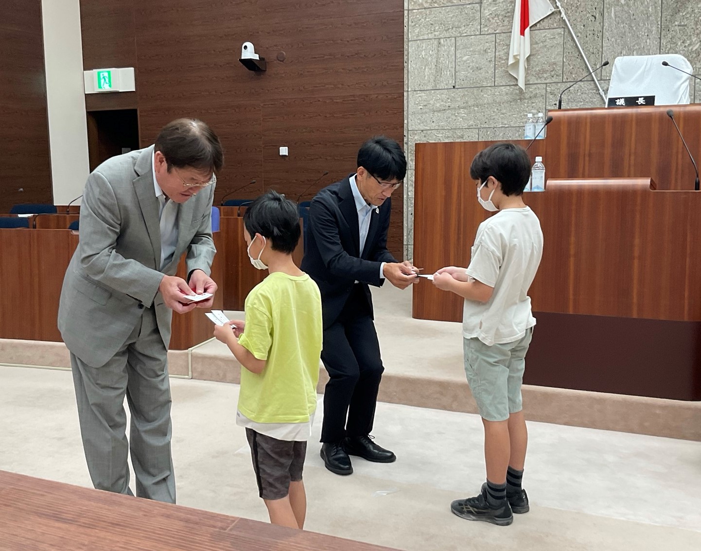 スーツ姿の議員が、子どもたちと名刺交換をしている様子の写真