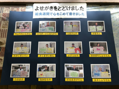 「よせがきをとどけました 給食週間で心をこめて書きました」と題が貼られた黒い台紙に、12枚の給食関係者が児童から贈られた寄せ書きを持つ写真が配置された掲示物