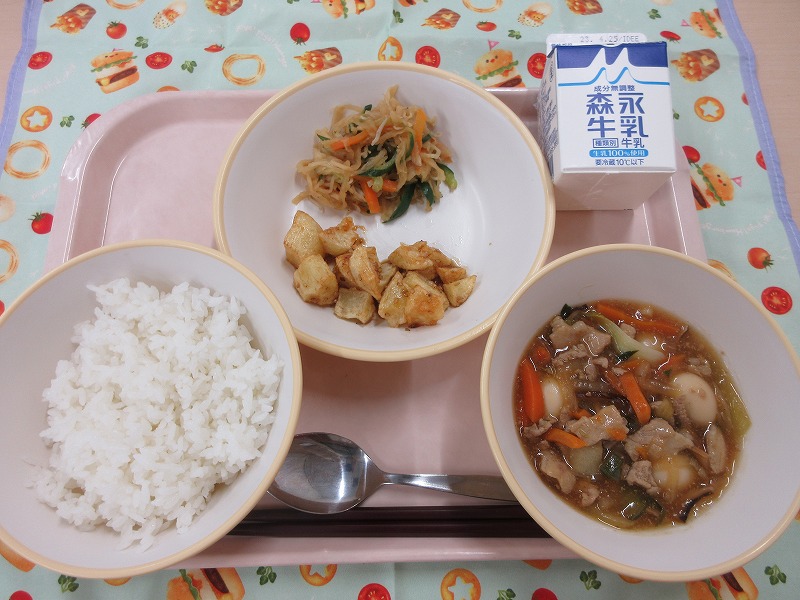 ピンクのトレーに給食が右上から反時計回りで牛乳、じゃがいものごまだれがけとはりはりサラダ、ご飯、八宝菜と並べられている写真