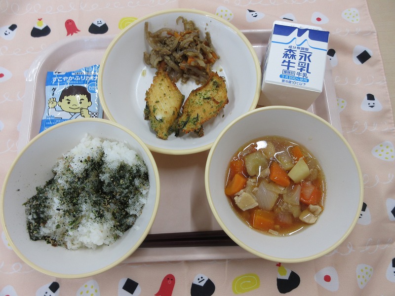 ピンクのトレーに給食が右上から反時計回りで牛乳、いかの港揚げときんぴら、ご飯（ふりかけ）、野菜の旨煮と並べられている写真