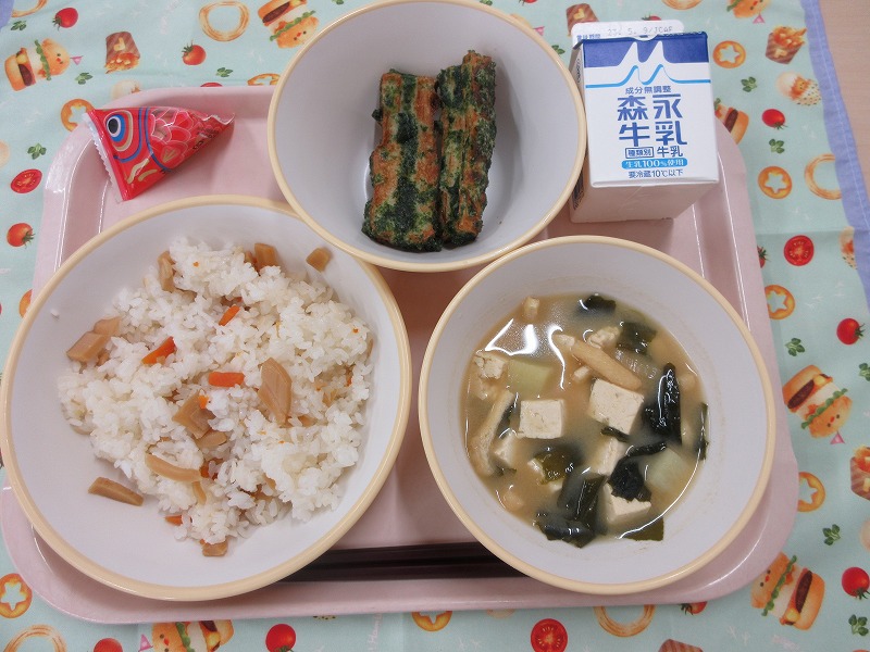 ピンクのトレーに給食が右上から反時計回りで牛乳、ちくわの磯辺揚げ、こいボーロ、たけのこごはん、具だくさん味噌汁と並べられている写真