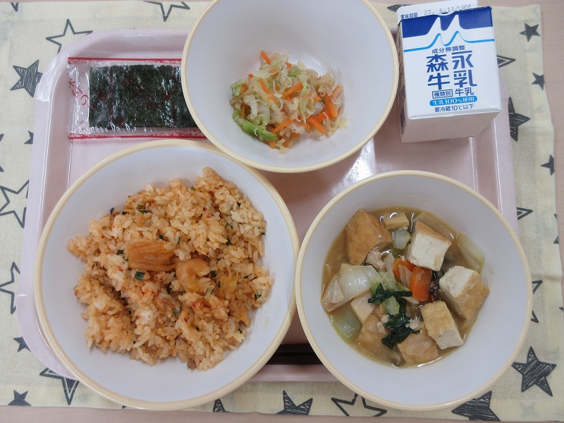 ピンクのトレーに給食が右上から反時計回りで牛乳、じゃこサラダ、味つけのり、キムチまぜごはん、生揚げの中華煮と並べられている写真