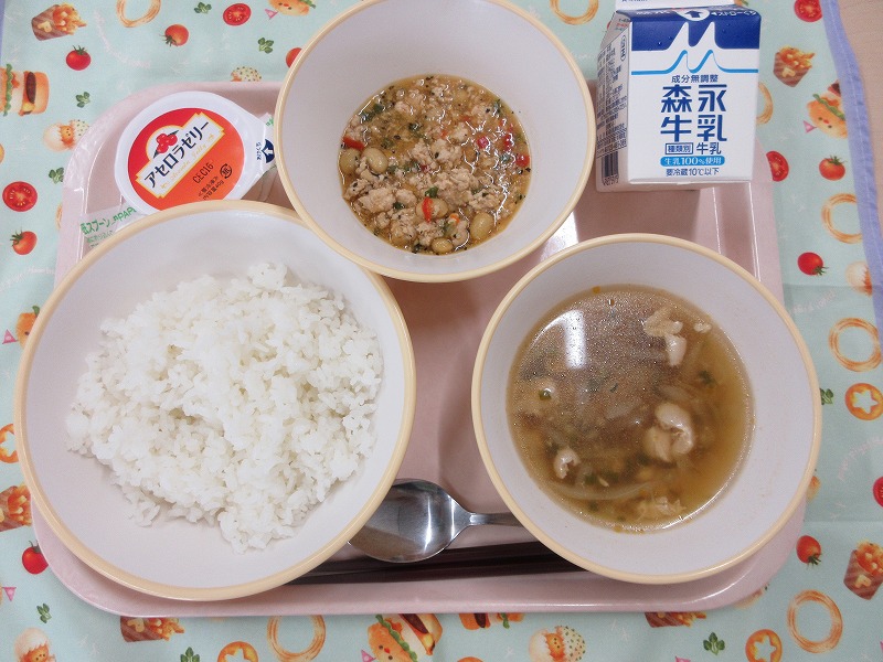 ピンクのトレーに給食が右上から反時計回りで牛乳、ガパオライスの具、アセロラゼリー、ごはん、鶏肉と春雨のアジアンスープと並べられている写真