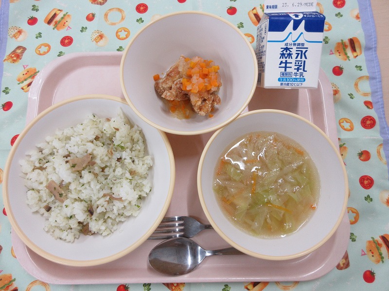 ピンクのトレーに給食が右上から反時計回りで牛乳、鶏肉のマリネ、ベーコンピラフ、コンソメスープと並べられている写真