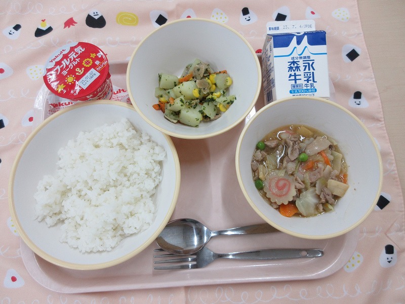 ピンクのトレーに給食が右上から反時計回りで牛乳、じゃがいものソテー、ヨーグルト、ごはん、中華丼の具と並べられている写真