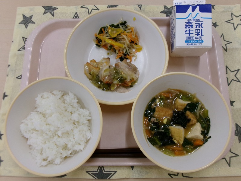 ピンクのトレーに給食が右上から反時計回りで牛乳、しらたきサラダと鶏肉のねぎ塩焼き、ごはん、中華うま煮と並べられている写真