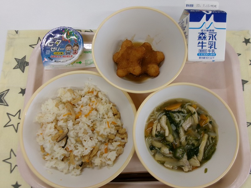 ピンクのトレーに給食が右上から反時計回りで牛乳、星のコロッケ、七夕ゼリー、かしわ寿司、七夕汁と並べられている写真