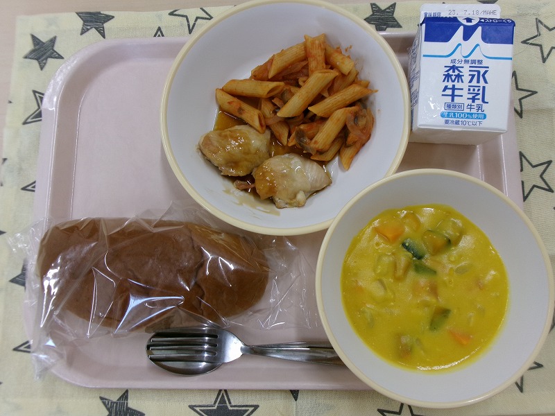 ピンクのトレーに給食が右上から反時計回りで牛乳、なすのペンネアラビアータとてりチキン、黒パン、豆乳かぼちゃスープと並べられている写真