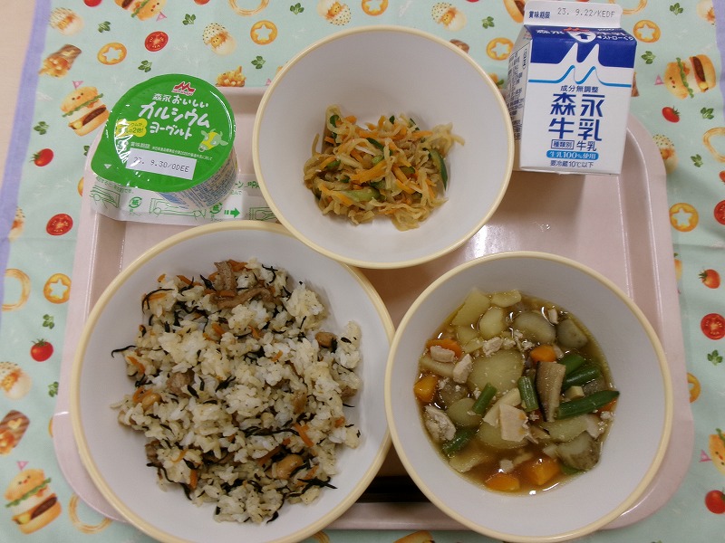 ピンクのトレーに給食が右上から反時計回りで牛乳、はりはりサラダ、ヨーグルト、ひじきごはん、筑前煮と並んでいる写真